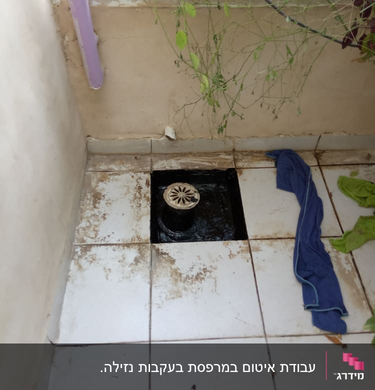 פתח ניקוז מרובע עם מכסה עגול על רצפה מלוכלכת